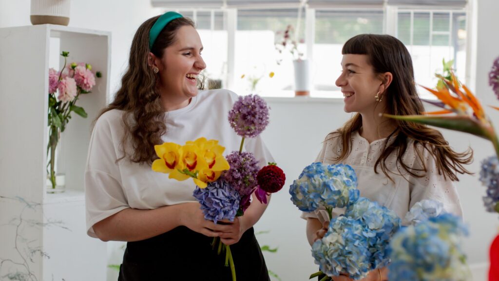 two women smiling holding flowers