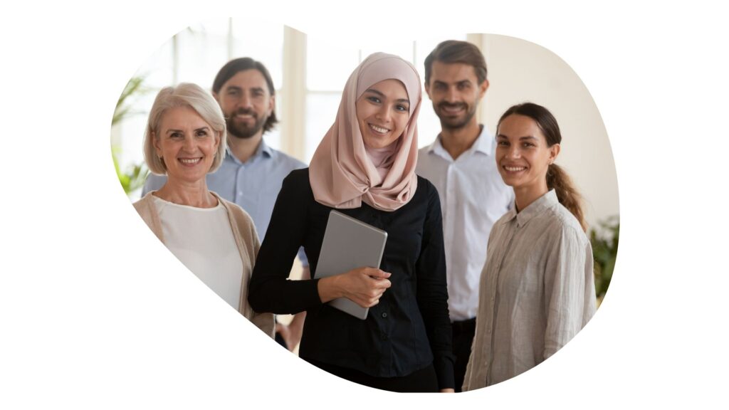 five people standing and looking at the camera, including a hijabi woman.